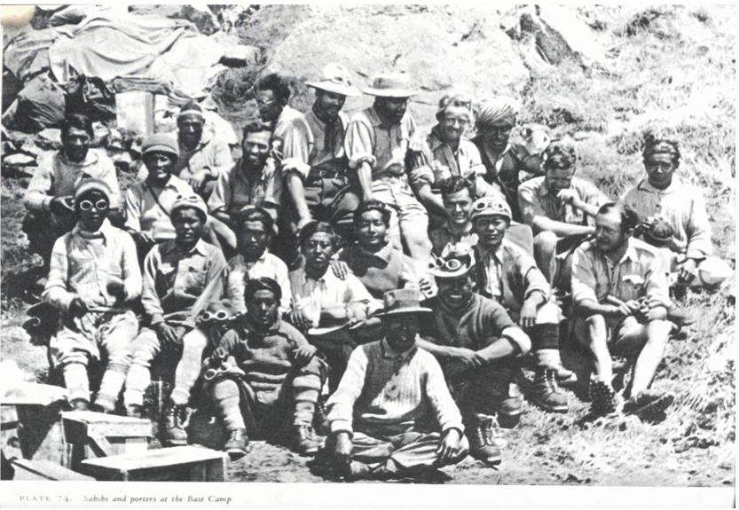 The picture shows 22 men sitting in three rows on an ascending slope posing for a picture.